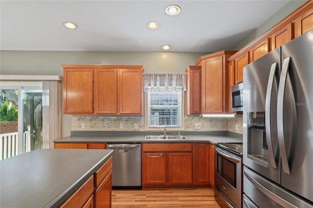 15613 Charmwood Dr, Hudson, FL 34667 - kitchen featuring appliances with stainless steel finishes, a sink, tasteful backsplash, light wood-style floors, and dark countertops