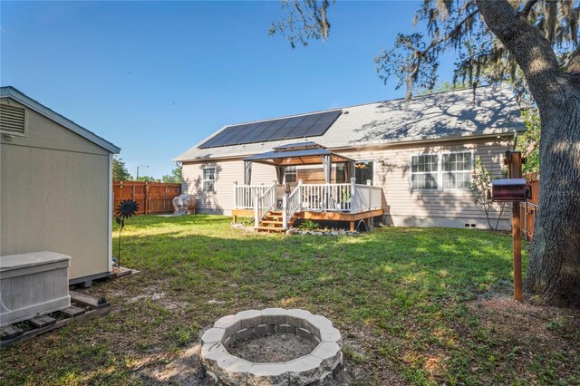 15613 Charmwood Dr, Hudson, FL 34667 - back of house featuring a fire pit, a wooden deck, solar panels, crawl space, and a gazebo