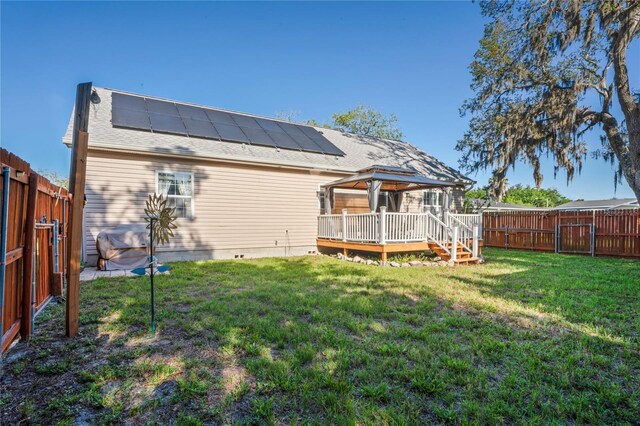 15613 Charmwood Dr, Hudson, FL 34667 - rear view of house featuring a gazebo, a deck, roof mounted solar panels, and a shingled roof