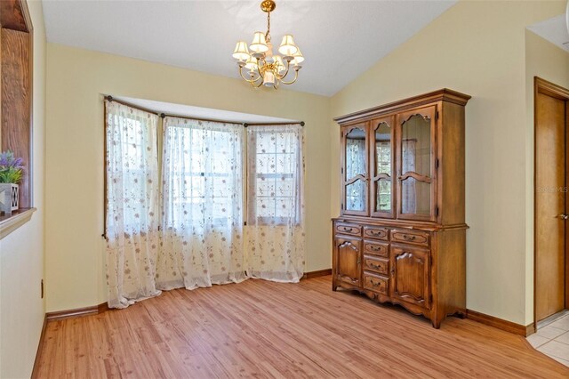 8402 Lake Hill Ct, Spring Hill, FL 34608 - foyer featuring a chandelier, light wood-type flooring, plenty of natural light, baseboards, and lofted ceiling
