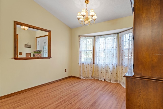 8402 Lake Hill Ct, Spring Hill, FL 34608 - spare room with wood finished floors, a chandelier, healthy amount of natural light, vaulted ceiling, and baseboards