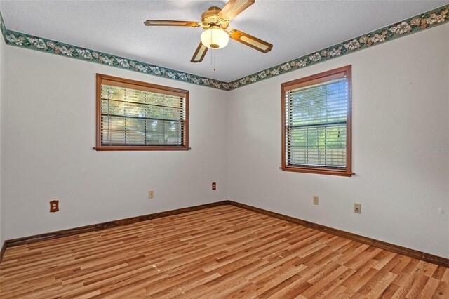 8402 Lake Hill Ct, Spring Hill, FL 34608 - unfurnished room featuring plenty of natural light, light wood finished floors, a textured ceiling, baseboards, and a ceiling fan