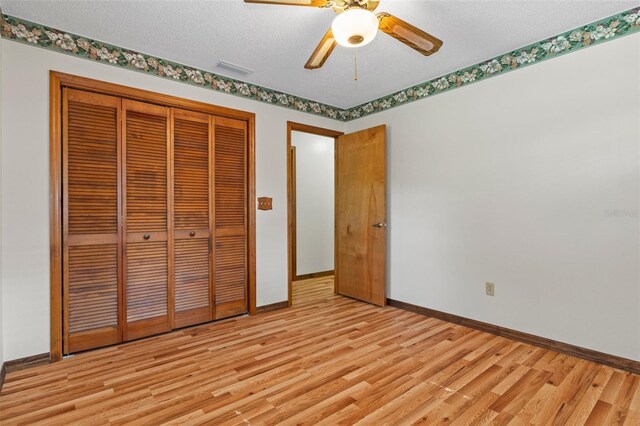 8402 Lake Hill Ct, Spring Hill, FL 34608 - unfurnished bedroom with light wood-style flooring, baseboards, a closet, a ceiling fan, and a textured ceiling