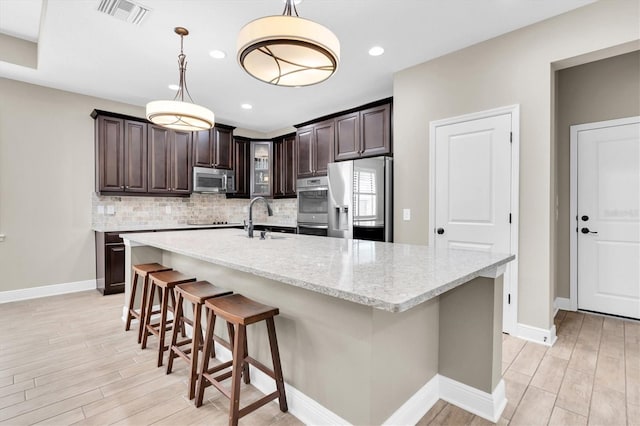 12420 Rangeland Blvd, Odessa, FL 33556 - kitchen featuring stainless steel appliances, backsplash, light wood-style floors, dark brown cabinetry, and recessed lighting