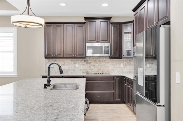 12420 Rangeland Blvd, Odessa, FL 33556 - kitchen featuring stainless steel appliances, a sink, dark brown cabinets, tasteful backsplash, and light wood-style floors