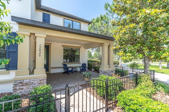 12420 Rangeland Blvd, Odessa, FL 33556 - property entrance featuring covered porch, stucco siding, stone siding, and a gate