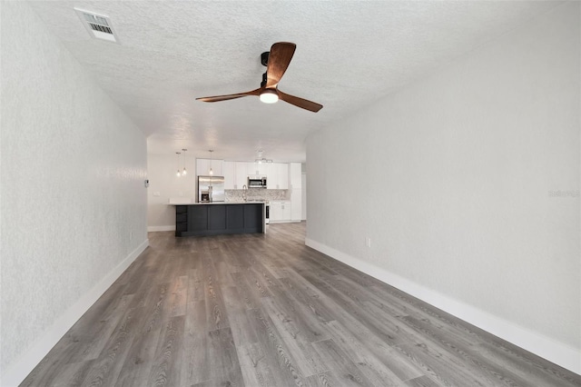 4482 Kingston Dr, Hernando Beach, FL 34607 - unfurnished living room with a ceiling fan, wood finished floors, baseboards, and a textured ceiling
