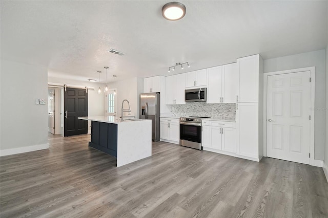 4482 Kingston Dr, Hernando Beach, FL 34607 - kitchen with appliances with stainless steel finishes, a barn door, white cabinets, tasteful backsplash, and wood finished floors