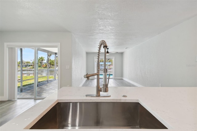 4482 Kingston Dr, Hernando Beach, FL 34607 - detailed view of a sink, a textured ceiling, wood finished floors, and light stone countertops