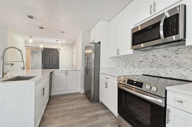4482 Kingston Dr, Hernando Beach, FL 34607 - kitchen featuring stainless steel appliances, a sink, light wood finished floors, decorative backsplash, and white cabinetry
