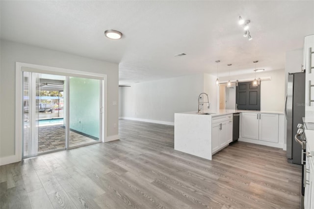 4482 Kingston Dr, Hernando Beach, FL 34607 - kitchen with a sink, a barn door, light wood-style flooring, open floor plan, and a peninsula