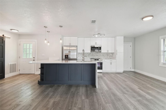 4482 Kingston Dr, Hernando Beach, FL 34607 - kitchen with stainless steel appliances, a barn door, light countertops, white cabinetry, and a textured ceiling