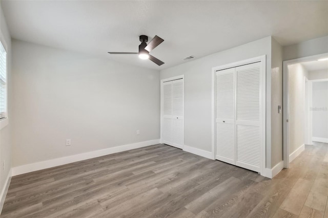 4482 Kingston Dr, Hernando Beach, FL 34607 - unfurnished bedroom with two closets, wood finished floors, baseboards, and a ceiling fan