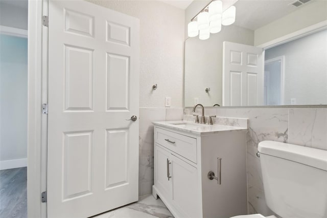 4482 Kingston Dr, Hernando Beach, FL 34607 - bathroom with tile walls, vanity, toilet, and a wainscoted wall