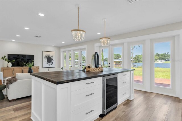 18102 Spencer Rd, Odessa, FL 33556 - kitchen with wine cooler, light wood finished floors, wooden counters, open floor plan, and white cabinetry
