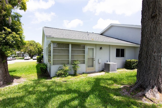 12511 Dearborn Dr, Hudson, FL 34667 - back of property featuring central AC, stucco siding, a lawn, and roof with shingles