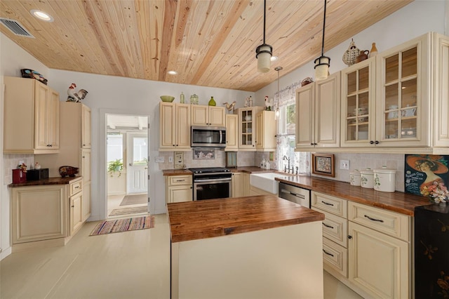 6207 Main St, New Port Richey, FL 34653 - kitchen featuring butcher block counters, stainless steel appliances, cream cabinets, wood ceiling, and healthy amount of natural light