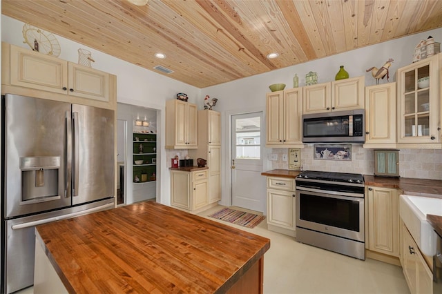 6207 Main St, New Port Richey, FL 34653 - kitchen with stainless steel appliances, cream cabinets, butcher block counters, wood ceiling, and backsplash