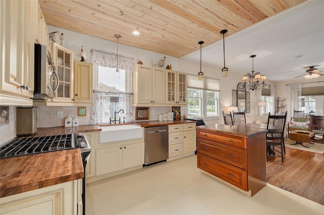 6207 Main St, New Port Richey, FL 34653 - kitchen featuring butcher block counters, appliances with stainless steel finishes, cream cabinets, and decorative backsplash