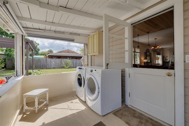 6207 Main St, New Port Richey, FL 34653 - laundry area featuring cabinet space, healthy amount of natural light, wooden ceiling, a chandelier, and washing machine and dryer