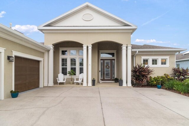 16697 Courtyard Loop, Land O Lakes, FL 34638 - view of exterior entry featuring stucco siding, driveway, a porch, and an attached garage