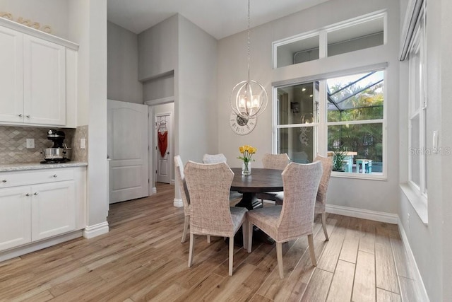 16697 Courtyard Loop, Land O Lakes, FL 34638 - dining room featuring light wood-type flooring, a chandelier, and a towering ceiling