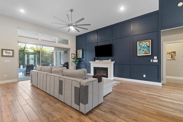 16697 Courtyard Loop, Land O Lakes, FL 34638 - living room with ceiling fan, light wood-style flooring, a glass covered fireplace, and a decorative wall