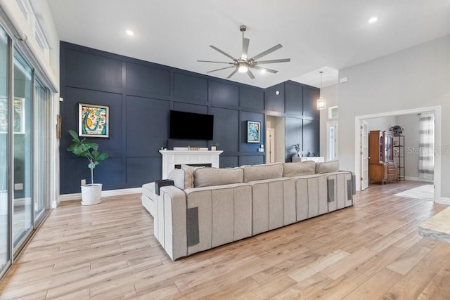 16697 Courtyard Loop, Land O Lakes, FL 34638 - living room featuring ceiling fan, light wood-style floors, a high ceiling, and a decorative wall