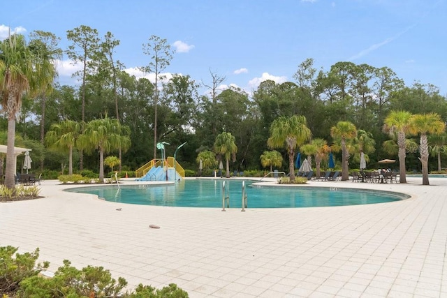 16697 Courtyard Loop, Land O Lakes, FL 34638 - community pool featuring a patio, view of scattered trees, and a water slide