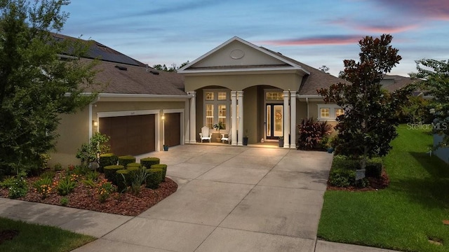 16697 Courtyard Loop, Land O Lakes, FL 34638 - view of front of house featuring driveway, stucco siding, an attached garage, a front yard, and covered porch