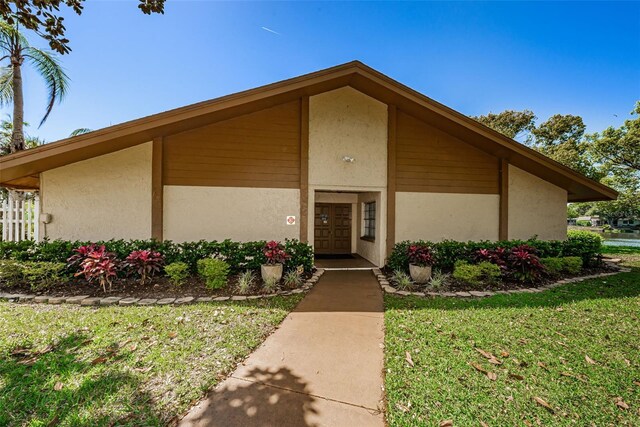 3838 Lanyard Ct Unit B, New Port Richey, FL 34652 - view of exterior entry featuring stucco siding and a lawn