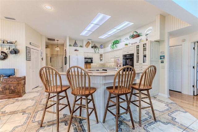 8132 Summersong Ct, Spring Hill, FL 34606 - kitchen with black appliances, a kitchen bar, glass insert cabinets, and white cabinetry