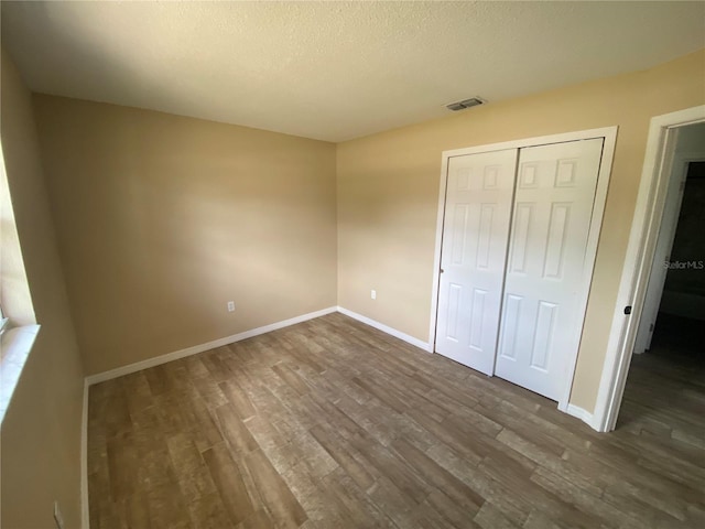 11392 Beechdale Ave, Spring Hill, FL 34608 - unfurnished bedroom with dark wood finished floors, baseboards, a closet, and a textured ceiling