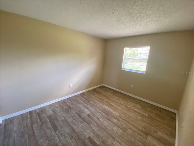 11392 Beechdale Ave, Spring Hill, FL 34608 - empty room with a textured ceiling, wood finished floors, and baseboards