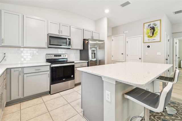3886 Reflection Dock Dr, Seffner, FL 33584 - kitchen with stainless steel appliances, a kitchen island, decorative backsplash, a breakfast bar area, and light stone countertops