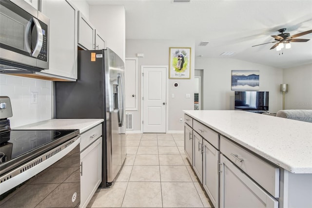 3886 Reflection Dock Dr, Seffner, FL 33584 - kitchen featuring appliances with stainless steel finishes, a ceiling fan, open floor plan, tasteful backsplash, and light stone countertops