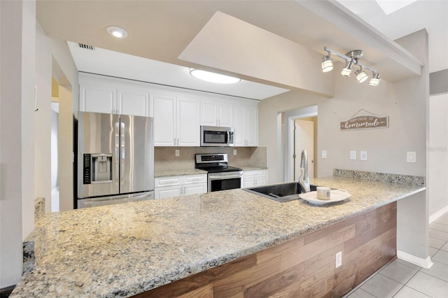 11291 Countrywood Ct, Spring Hill, FL 34609 - kitchen with stainless steel appliances, a peninsula, a sink, and white cabinetry
