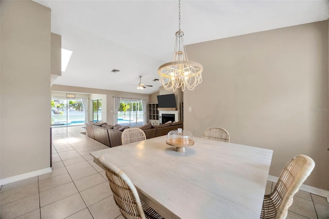 11291 Countrywood Ct, Spring Hill, FL 34609 - dining area featuring a fireplace, ceiling fan, light tile patterned floors, baseboards, and vaulted ceiling