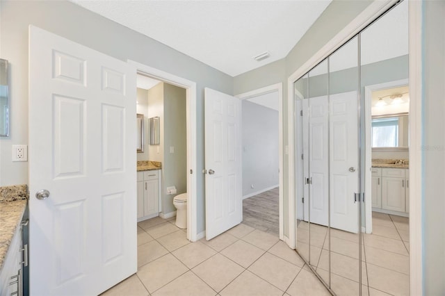 11291 Countrywood Ct, Spring Hill, FL 34609 - unfurnished bedroom with light tile patterned flooring, a closet, ensuite bathroom, baseboards, and a sink