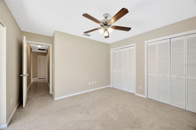 11291 Countrywood Ct, Spring Hill, FL 34609 - unfurnished bedroom featuring light colored carpet, multiple closets, baseboards, and a ceiling fan