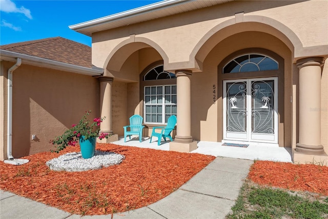 5423 Abagail Dr, Spring Hill, FL 34608 - doorway to property featuring stucco siding, a shingled roof, covered porch, and french doors