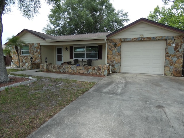 7421 Fairfax Dr, Port Richey, FL 34668 - ranch-style home featuring stone siding, covered porch, concrete driveway, and a garage