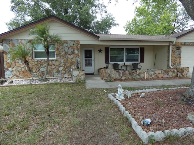 7421 Fairfax Dr, Port Richey, FL 34668 - ranch-style home with stone siding, a porch, and an attached garage