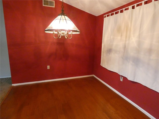 7421 Fairfax Dr, Port Richey, FL 34668 - unfurnished room with wood finished floors, a chandelier, baseboards, and lofted ceiling