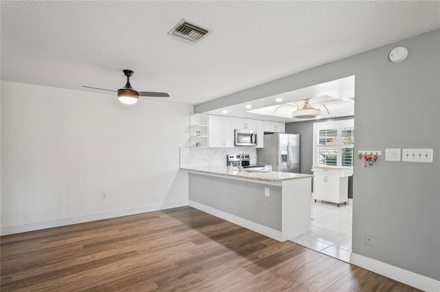 9622 Brassie Ct Unit 9, New Port Richey, FL 34655 - kitchen featuring appliances with stainless steel finishes, open shelves, a peninsula, white cabinets, and a textured ceiling