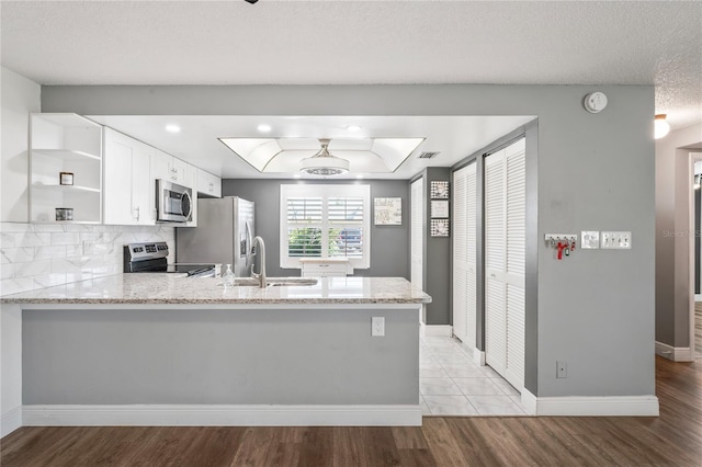 9622 Brassie Ct Unit 9, New Port Richey, FL 34655 - kitchen featuring stainless steel appliances, open shelves, a peninsula, a sink, and light stone counters