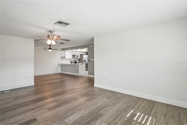 9622 Brassie Ct Unit 9, New Port Richey, FL 34655 - unfurnished living room featuring dark wood-type flooring, baseboards, a ceiling fan, and a textured ceiling