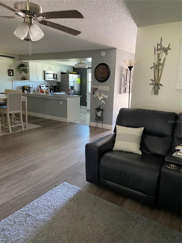 9622 Brassie Ct Unit 9, New Port Richey, FL 34655 - living room featuring light wood-style floors, a ceiling fan, a textured ceiling, and baseboards