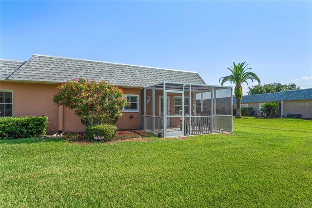 9622 Brassie Ct Unit 9, New Port Richey, FL 34655 - rear view of property featuring roof with shingles, stucco siding, a yard, mansard roof, and a sunroom