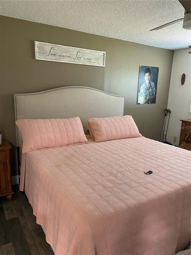 9622 Brassie Ct Unit 9, New Port Richey, FL 34655 - bedroom featuring dark wood-style flooring, a textured ceiling, and a ceiling fan